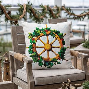 A square throw pillow with a nautical Christmas design featuring a golden ship's wheel surrounded by green holly leaves and red berries, resting on a wooden outdoor patio chair.