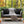 Gray sofa with black pillows and a blanket on a wooden deck with Halloween decorations.