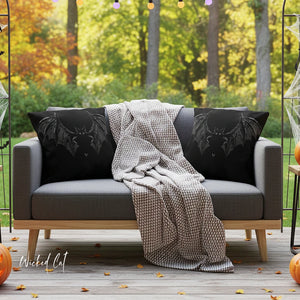 Gray sofa with black pillows and a blanket on a wooden deck with Halloween decorations.