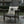 Wooden chair with a decorative pillow featuring text and graphics on a patio.