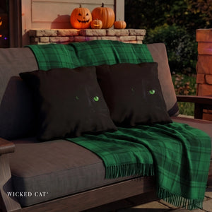 Two black pillows with the face of a cat with green eyes on an outdoor patio