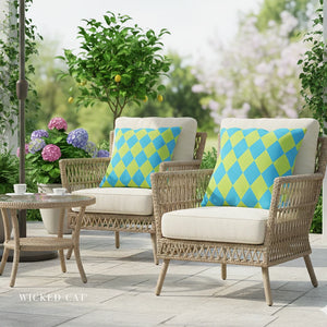 Outdoor patio set with wicker chairs, table, and colorful cushions in a garden setting.