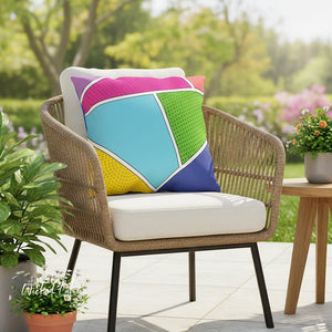 Wicker chair with a colorful geometric pillow on a patio with plants and flowers.