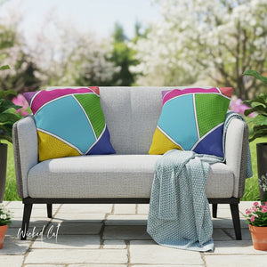 Gray outdoor sofa with colorful geometric cushions and a blanket, set against a garden backdrop.