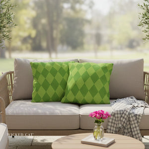 Outdoor sofa with green patterned cushions and a small table with flowers, set against a blurred natural background.
