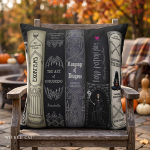 A decorative throw pillow with a gothic book spine design is displayed on a wooden chair in an outdoor autumn setting with pumpkins and trees in the background.