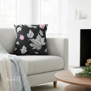 Decorative pillow with leaf pattern on a gray sofa in a living room setting.