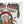 A square white throw pillow featuring a vintage-style Christmas graphic with the text 'Mama Claus' and 'Premium Holiday Spirits,' an illustration of an elderly woman in a Santa hat holding bottles, holly leaves, pinecones, and a small reindeer.