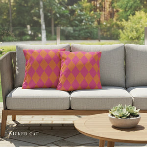 Gray outdoor sofa with pink and orange patterned cushions, set against a blurred garden background.