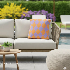 Outdoor patio setting with a beige sofa, colorful diamond-patterned pillow, and a small table with a plant.
