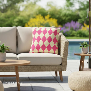 Outdoor patio set with a pink and white checkered pillow, blurred garden background