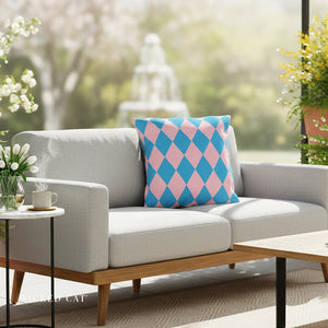Gray sofa with a colorful pillow in an outdoor setting with plants and a fountain.