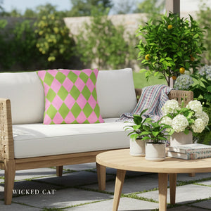 Outdoor patio setting with a white sofa, pink and green pillow, and a small table with plants and flowers.