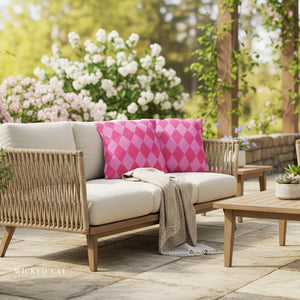 Outdoor patio set with wicker chairs and pink cushions in a garden setting.