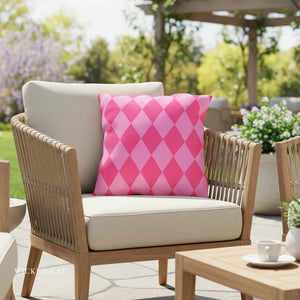 Outdoor chair with a pink and white patterned pillow in a garden setting