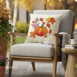 Decorative pillow with pumpkin and autumn leaves on a chair outdoors.