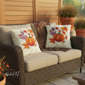 Outdoor patio set with decorative pillows featuring pumpkins and leaves on a wicker sofa.