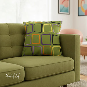 Green sofa with a colorful geometric pillow in a living room setting.
