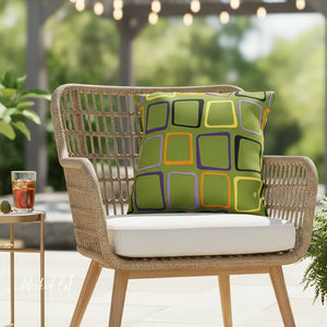 Wicker chair with a colorful pillow and a glass of iced tea on a patio