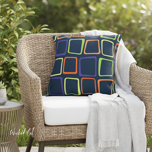 Wicker chair with a colorful geometric pillow and white cushion outdoors.