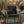 Wicker chair with a black pillow featuring a snake design, surrounded by Halloween decorations outdoors.