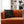 Black pillow with snake design on an orange couch in a living room setting.