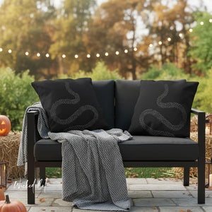 Black outdoor sofa with snake-patterned cushions on a patio with Halloween decorations.