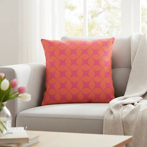 Orange and pink patterned pillow on a gray sofa with a blurred background