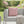Gray outdoor sofa with a pink and white patterned pillow, surrounded by greenery and flowers.