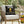 Chair with a pillow featuring 'Stings Brewing Co. Buzzzzed' design outdoors.