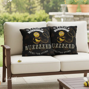 Two black pillows with bee designs on a white outdoor sofa.