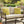 Outdoor patio set with beige cushions and yellow pillows featuring bee designs, surrounded by plants and a fountain.