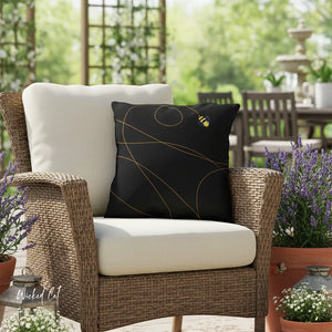 Wicker chair with white and black cushions in an outdoor setting with plants and a fountain.