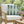 Chair with a green geometric pillow in an outdoor setting with flowers and a glass of iced tea.
