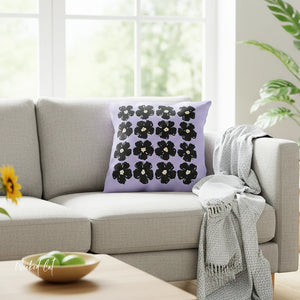 Decorative pillow with black floral pattern on a gray sofa in a bright living room.