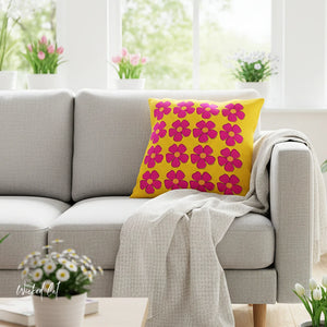 Yellow pillow with pink floral pattern on a gray sofa in a bright living room.