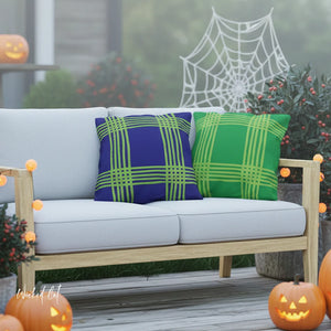 Outdoor seating area with blue and green plaid pillows, pumpkins, and a spider web decoration.