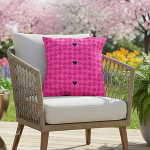 Chair with a pink pillow featuring black heart patterns in a garden setting