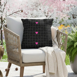 Decorative pillow with pink hearts on a chair in an outdoor setting with cherry blossoms.