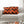 Orange and black chevron patterned pillow on a gray sofa with Halloween decorations in the foreground.