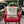 A square throw pillow with a Christmas tree graphic and the text 'WOODSTOCKS Organically Grown Christmas Trees' resting on a red armchair in a decorated outdoor patio setting.