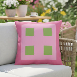 Pink pillow with green squares on a chair outdoors
