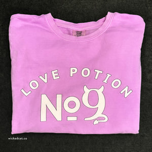 Folded pink sweatshirt with 'Love Potion No. 9' text and cat graphic on a black background