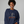 Person wearing a navy sweatshirt with a skeleton design and text, on a plain background