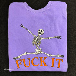 Folded purple sweatshirt with a skeleton and 'FUCK IT' text on a black background