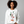 Woman wearing a white sweatshirt with a Christmas tree design on a gray background