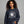 Woman wearing a dark grey sweatshirt with 'Bates Motel' design on a gray background