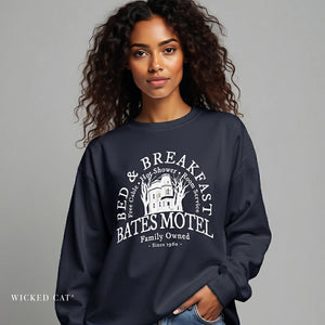 Woman wearing a dark grey sweatshirt with 'Bates Motel' design on a gray background