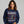 Woman wearing a navy blue sweatshirt with a skeleton design and text on a gray background
