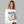 Woman wearing a white sweatshirt with a skeleton design and text on a gray background